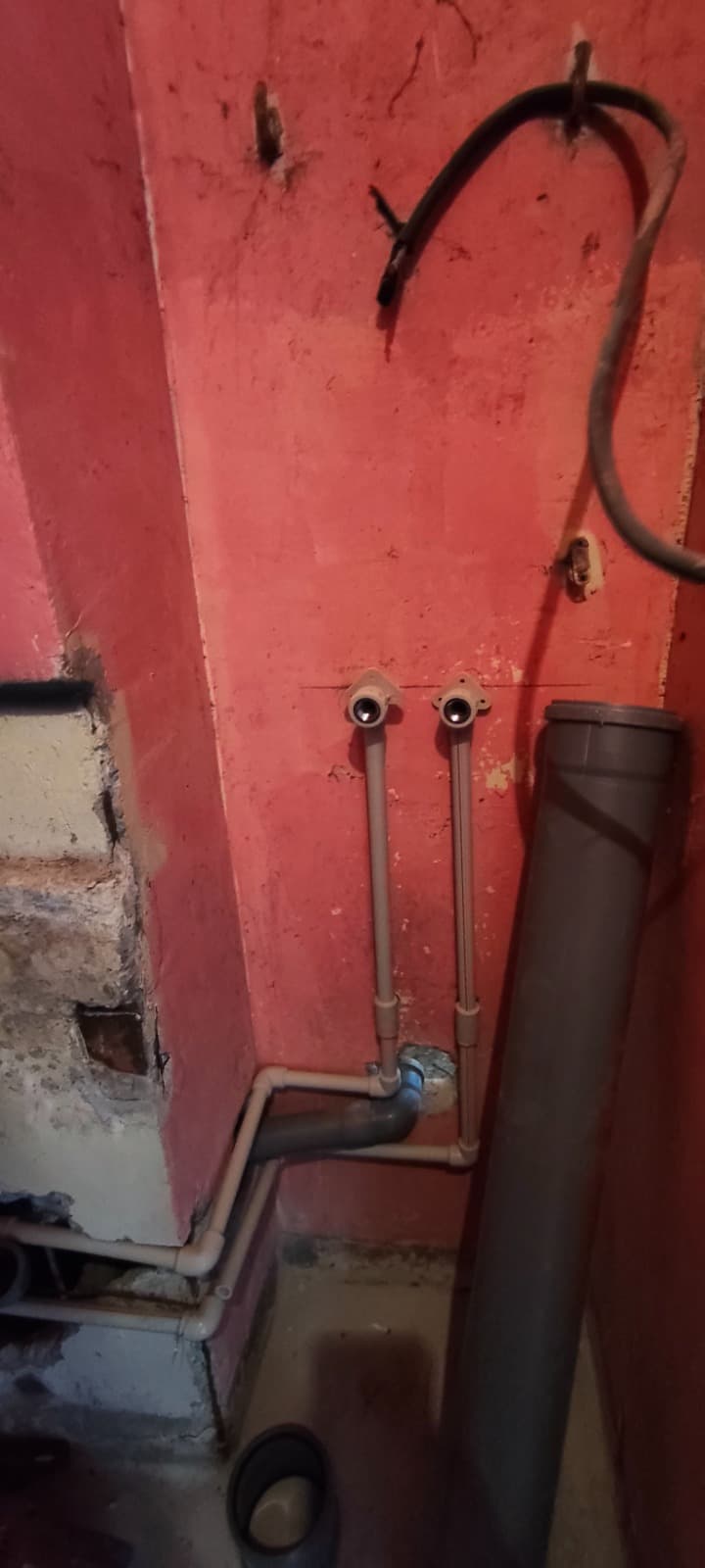 Нови водопроводни тръби с два извода и канализационна тръба, монтирани по стена в баня преди облицовката